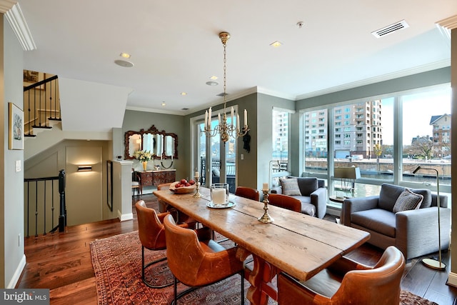 dining space with a notable chandelier, crown molding, and dark wood-type flooring