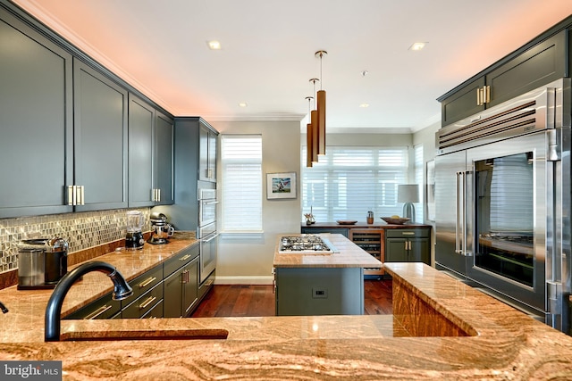 kitchen featuring sink, appliances with stainless steel finishes, a center island, wine cooler, and light stone countertops