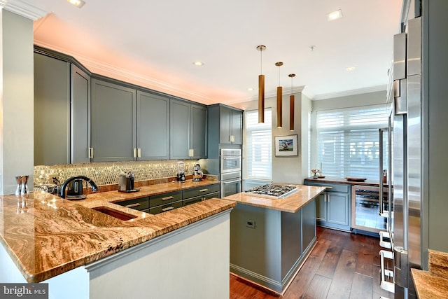 kitchen featuring sink, a center island, kitchen peninsula, stainless steel appliances, and light stone countertops