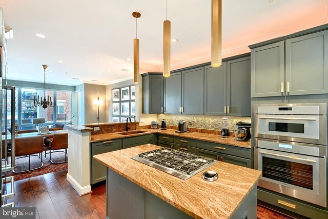 kitchen featuring a kitchen island, decorative light fixtures, sink, kitchen peninsula, and stainless steel appliances