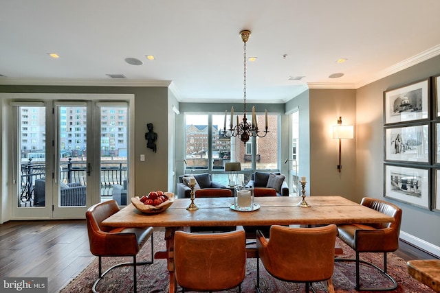 dining space featuring dark wood-type flooring, ornamental molding, and a notable chandelier