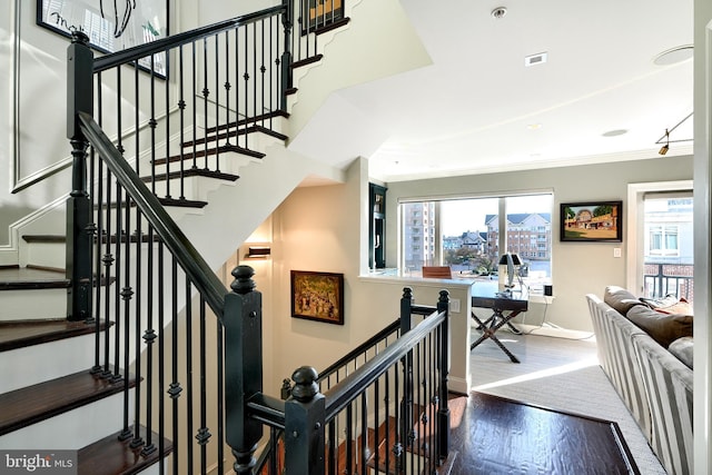 stairway with crown molding, a healthy amount of sunlight, and hardwood / wood-style floors