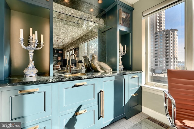 bar with sink, dark stone countertops, and light hardwood / wood-style flooring