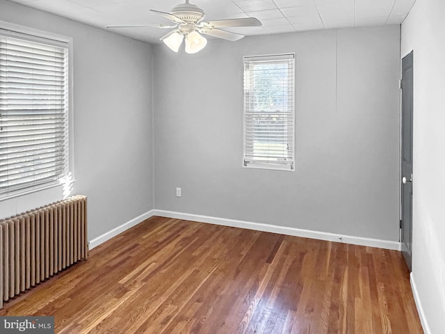 spare room featuring ceiling fan, radiator heating unit, and hardwood / wood-style floors