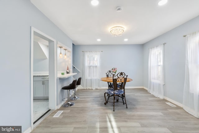 dining room featuring light wood-style floors, baseboards, visible vents, and a wealth of natural light