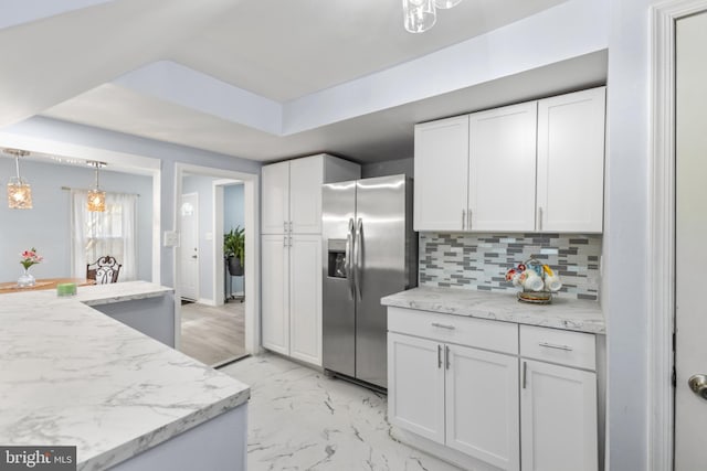 kitchen featuring marble finish floor, stainless steel fridge, white cabinets, and decorative backsplash