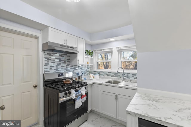 kitchen featuring under cabinet range hood, a sink, marble finish floor, stainless steel gas stove, and tasteful backsplash