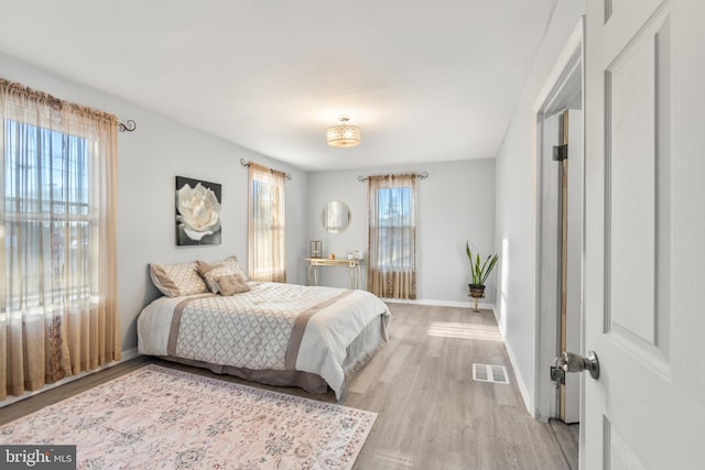 bedroom with baseboards, visible vents, and light wood-style floors