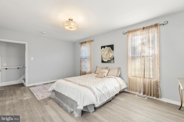 bedroom featuring visible vents, baseboards, and wood finished floors