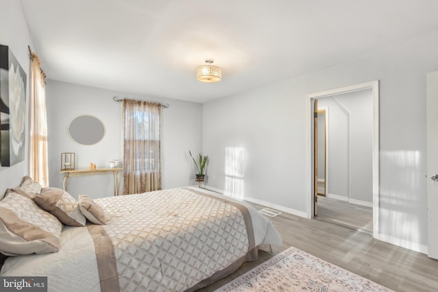 bedroom featuring baseboards, visible vents, and wood finished floors