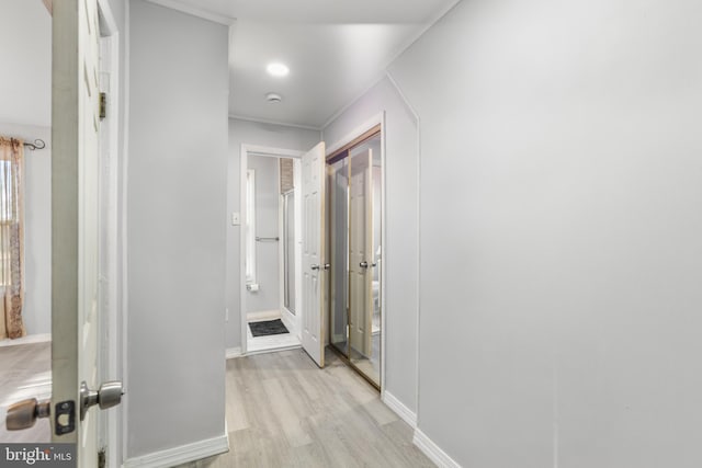 corridor featuring light wood-type flooring and baseboards