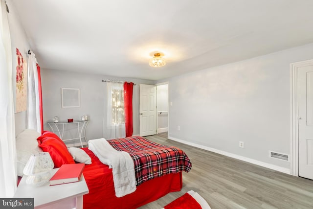 bedroom featuring wood finished floors, visible vents, and baseboards