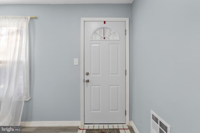 foyer with wood finished floors, visible vents, and baseboards