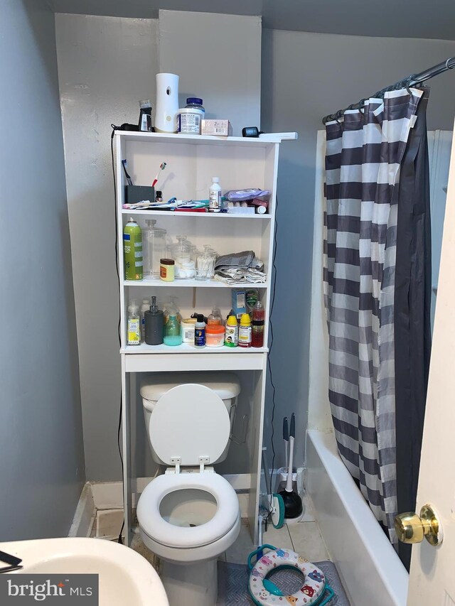 bathroom with toilet, tile patterned floors, and shower / bath combo with shower curtain