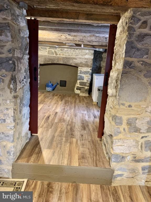 hallway featuring beam ceiling and hardwood / wood-style floors