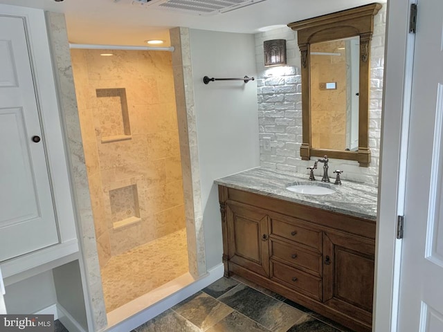 bathroom featuring a tile shower and vanity