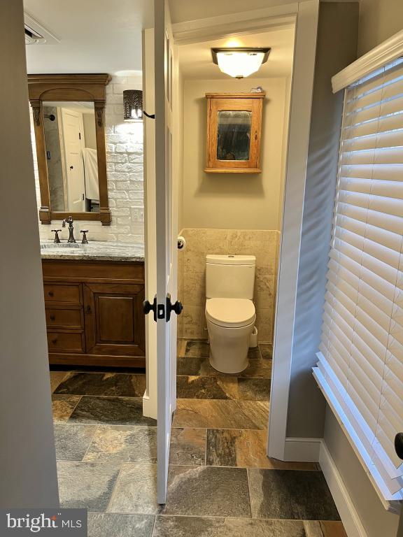 bathroom featuring vanity, tile walls, and toilet