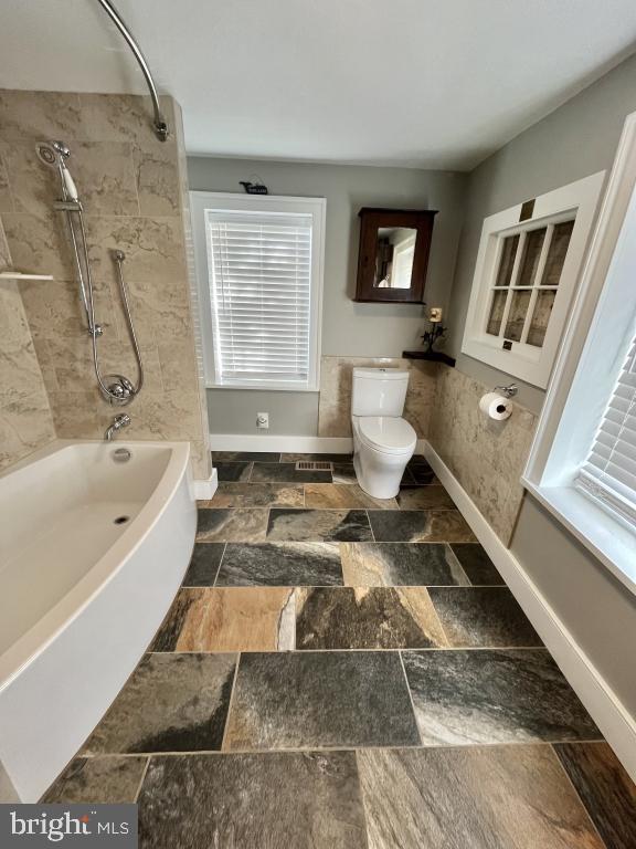 bathroom with toilet and tiled shower / bath