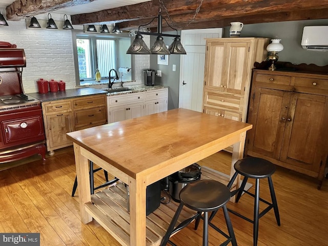 kitchen with pendant lighting, a wall mounted air conditioner, white cabinets, sink, and light wood-type flooring