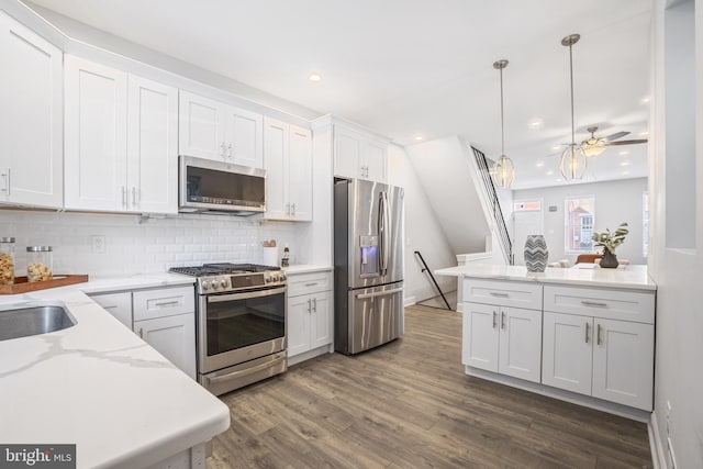 kitchen with white cabinetry, hanging light fixtures, appliances with stainless steel finishes, dark hardwood / wood-style floors, and decorative backsplash