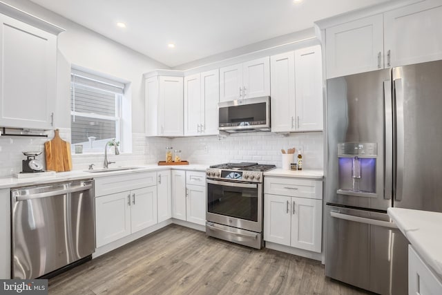 kitchen with appliances with stainless steel finishes, sink, decorative backsplash, and white cabinets