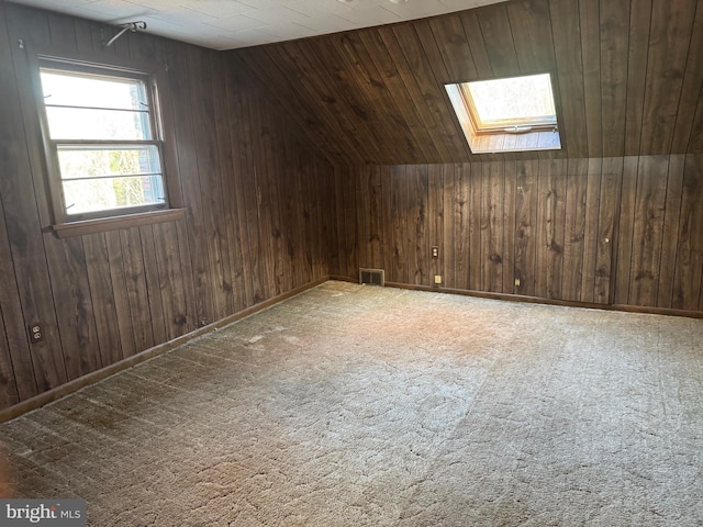 bonus room with wood walls, vaulted ceiling with skylight, light colored carpet, and wooden ceiling