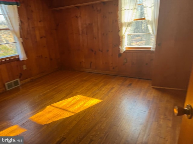 empty room with wooden walls and hardwood / wood-style floors