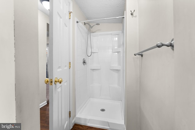 bathroom with wood-type flooring, a textured ceiling, and walk in shower