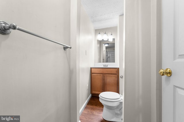 bathroom featuring a textured ceiling, vanity, hardwood / wood-style flooring, and toilet