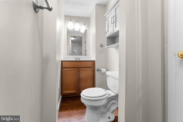 bathroom with vanity, a textured ceiling, hardwood / wood-style flooring, and toilet