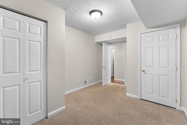 unfurnished bedroom with light colored carpet, a textured ceiling, and a closet