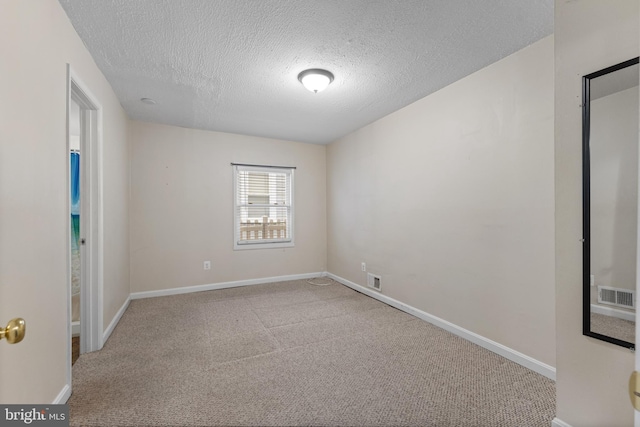 unfurnished room featuring light carpet and a textured ceiling