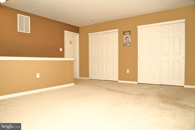 unfurnished bedroom featuring carpet flooring and two closets