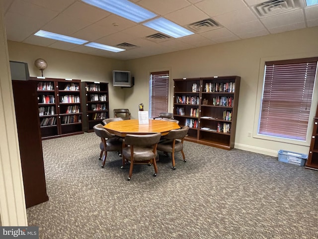 carpeted dining area featuring a paneled ceiling