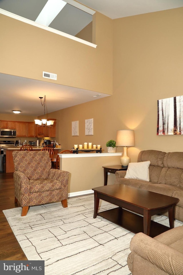 living room featuring an inviting chandelier, a towering ceiling, and light wood-type flooring