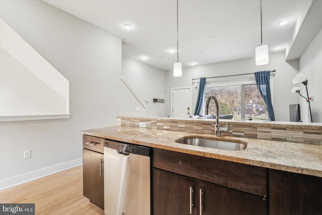 kitchen featuring light stone counters, sink, decorative light fixtures, dishwasher, and light hardwood / wood-style floors