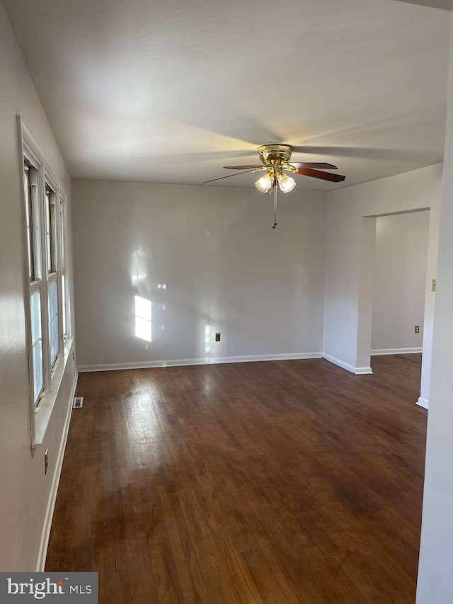 empty room with ceiling fan and dark wood-type flooring