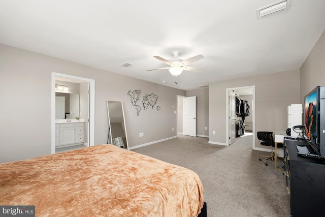 carpeted bedroom with ceiling fan, a spacious closet, ensuite bathroom, and a closet