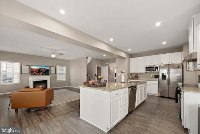 kitchen with white cabinets, dark hardwood / wood-style flooring, stainless steel appliances, and a kitchen island with sink