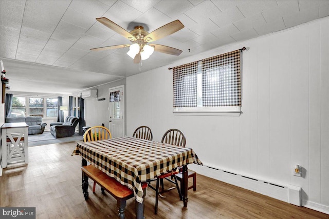 dining area featuring baseboard heating, ceiling fan, hardwood / wood-style floors, and a wall mounted air conditioner