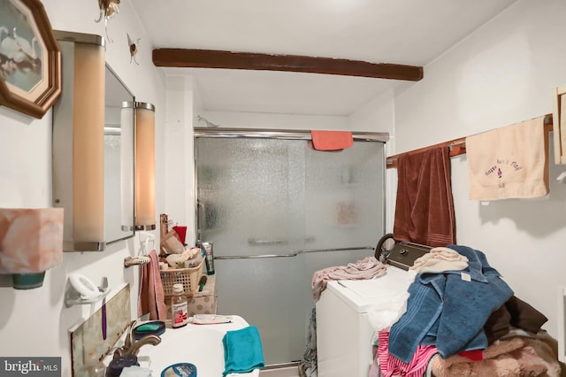 bathroom with washer and clothes dryer, beam ceiling, and walk in shower