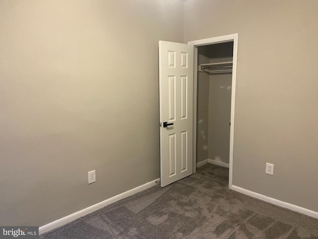 unfurnished bedroom featuring dark carpet and a closet