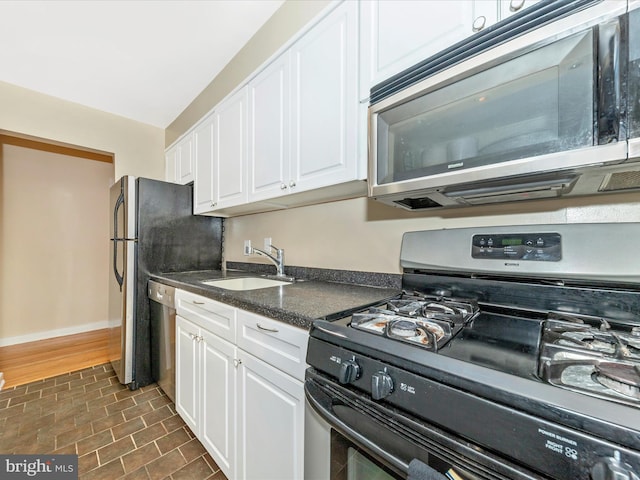 kitchen with white cabinetry, sink, stainless steel appliances, and dark hardwood / wood-style floors