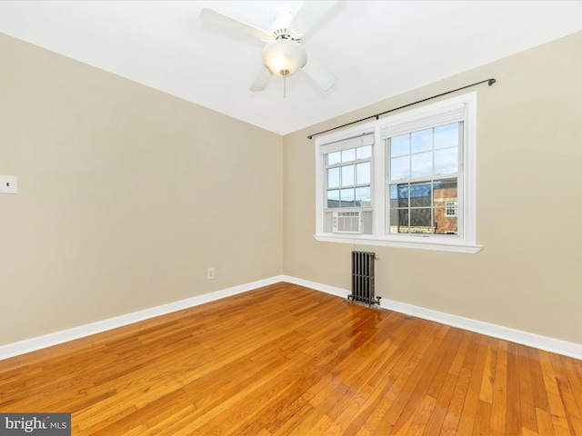 empty room featuring radiator, ceiling fan, and hardwood / wood-style flooring