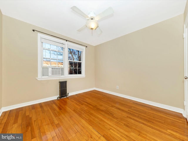 empty room featuring radiator heating unit, ceiling fan, cooling unit, and hardwood / wood-style floors