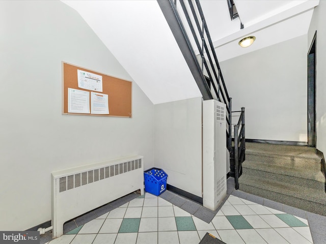 stairway with radiator and vaulted ceiling