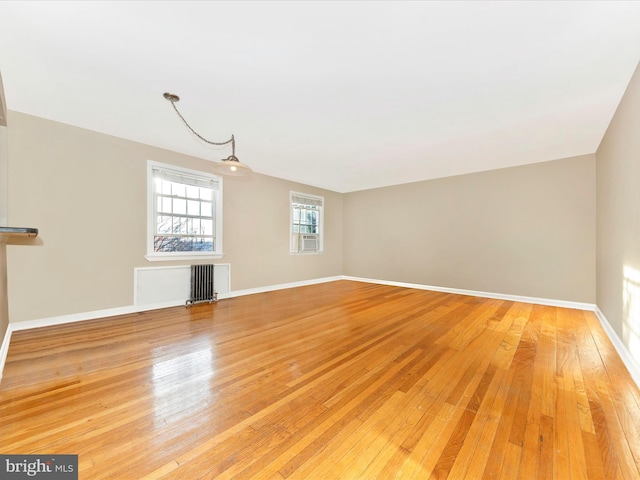 unfurnished living room featuring wood-type flooring and radiator heating unit