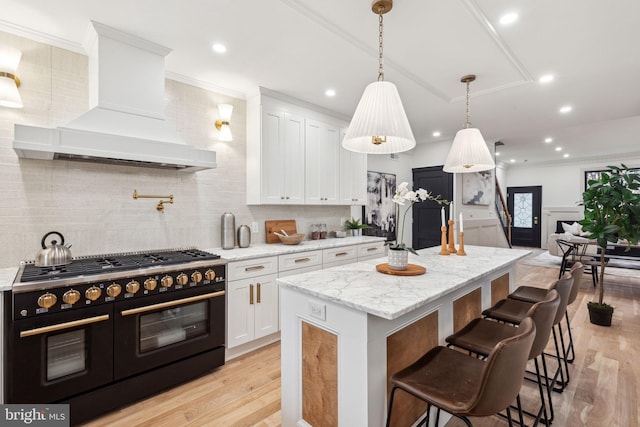 kitchen featuring premium range hood, white cabinetry, range with two ovens, and light wood-type flooring