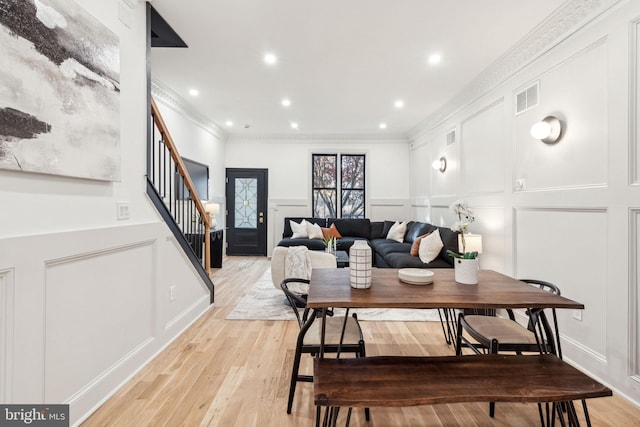 dining space with light hardwood / wood-style flooring and ornamental molding