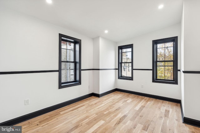 unfurnished room with plenty of natural light, light hardwood / wood-style floors, and lofted ceiling